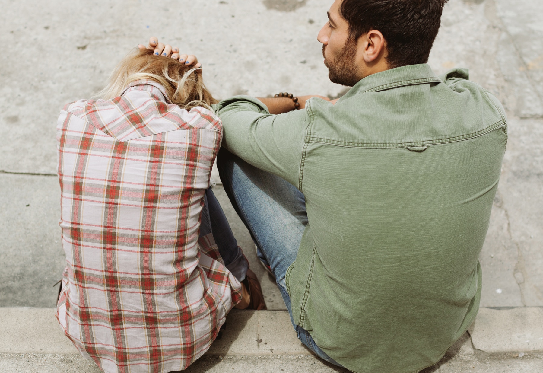 two persons sitting on cement pavement