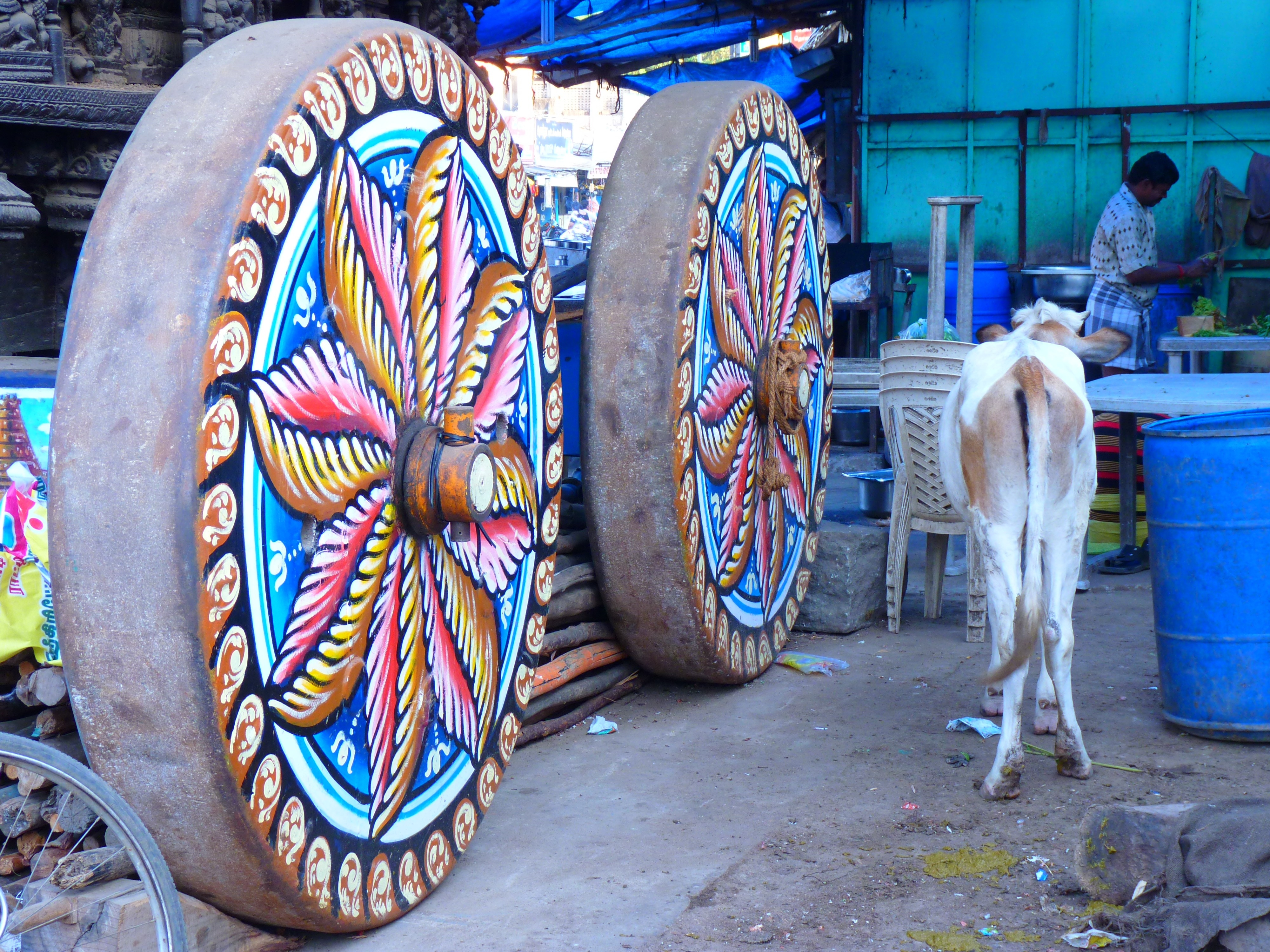 white 4 legged animal beside two round brass multi-colored large wheels