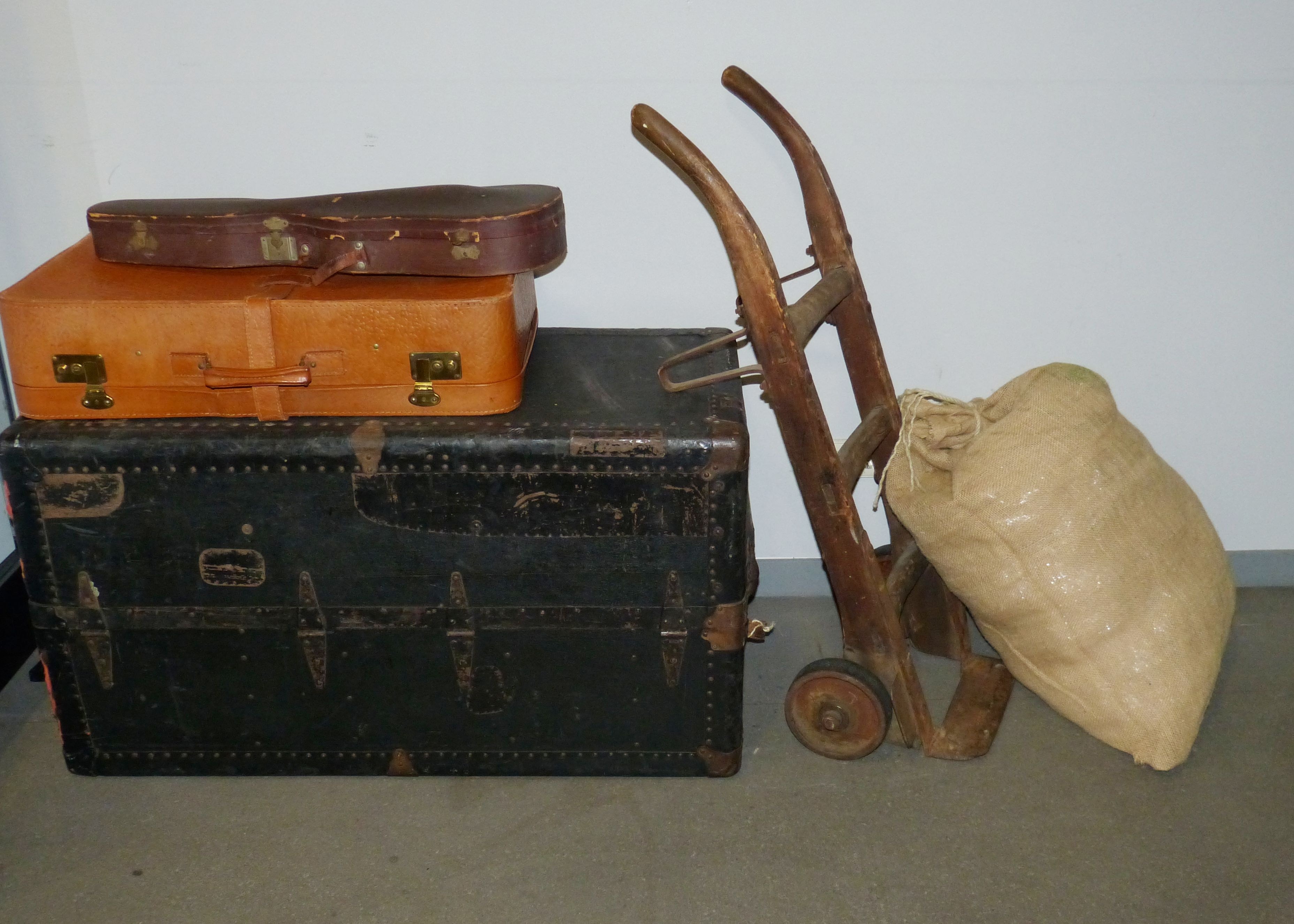 beige sack near brown wooden hand truck and black wooden chest box
