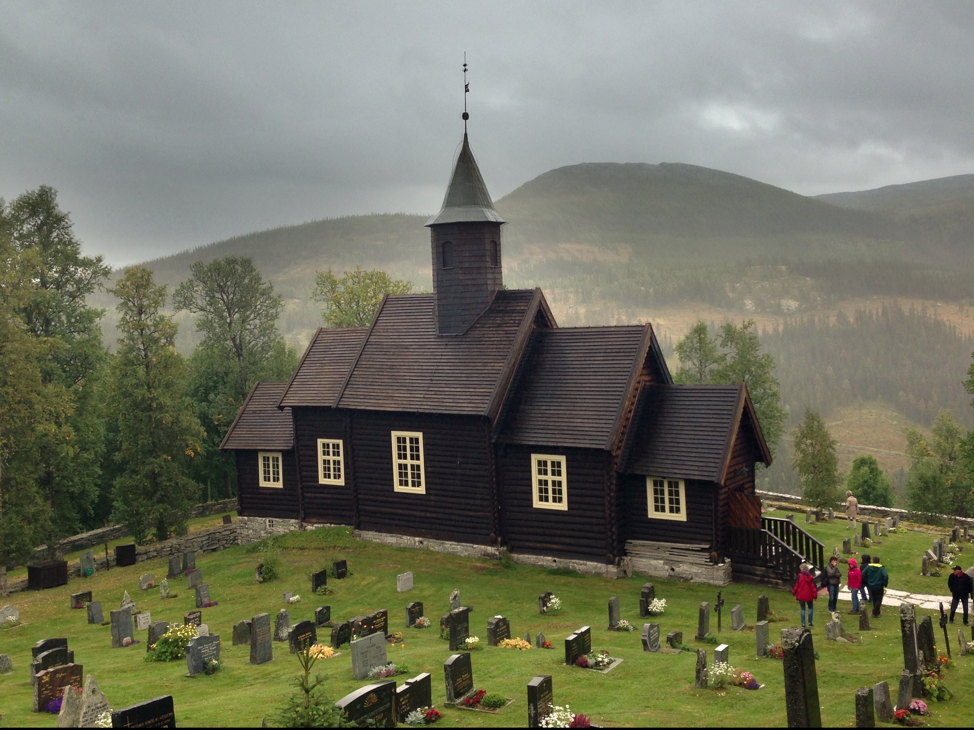 black church in middle of cemetery during cloudy daytime