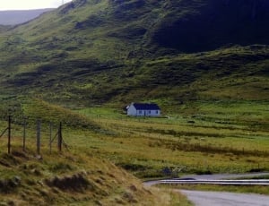 white and grey house near green field beside mountain thumbnail