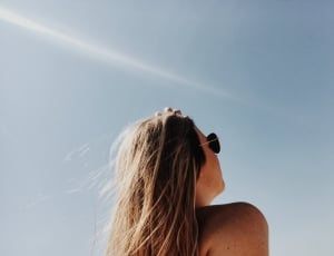 woman in aviator sunglasses looking up in the sky during daytime thumbnail