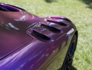 purple luxury car on green grass field thumbnail