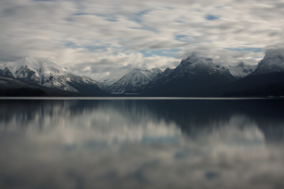 mirror image of snow covered mountains on body of water preview