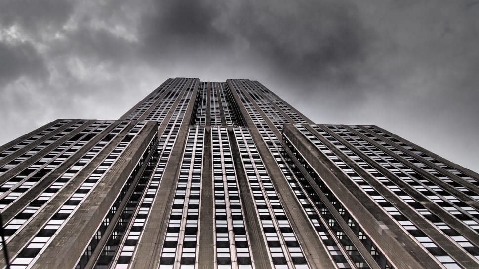 worm's eyeview of gray concrete building under black cloudy sky during daytime preview