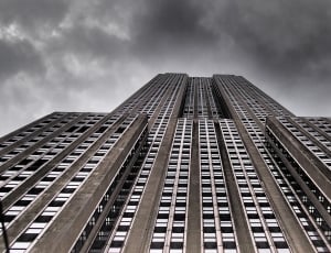 worm's eyeview of gray concrete building under black cloudy sky during daytime thumbnail