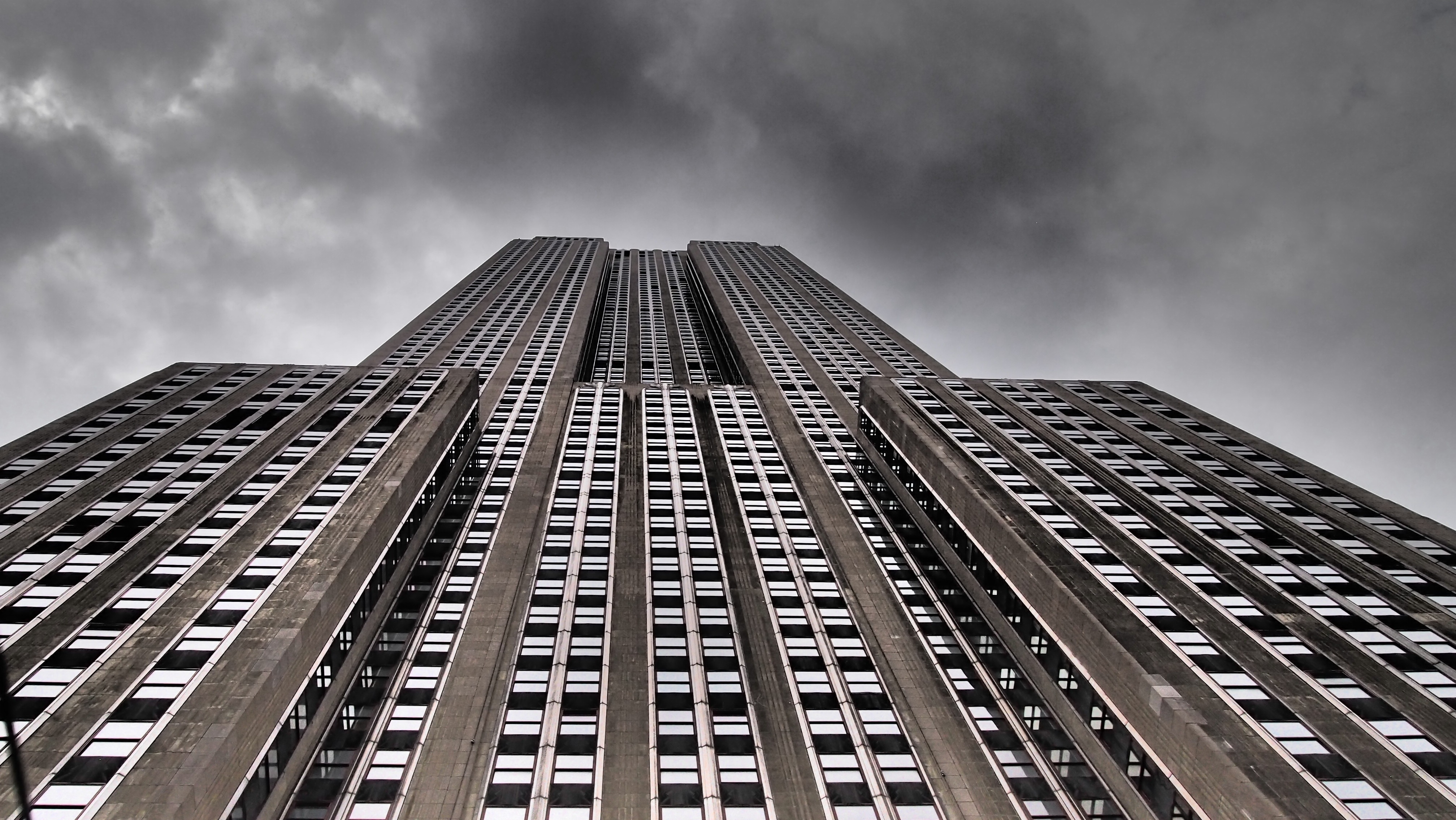 worm's eyeview of gray concrete building under black cloudy sky during daytime