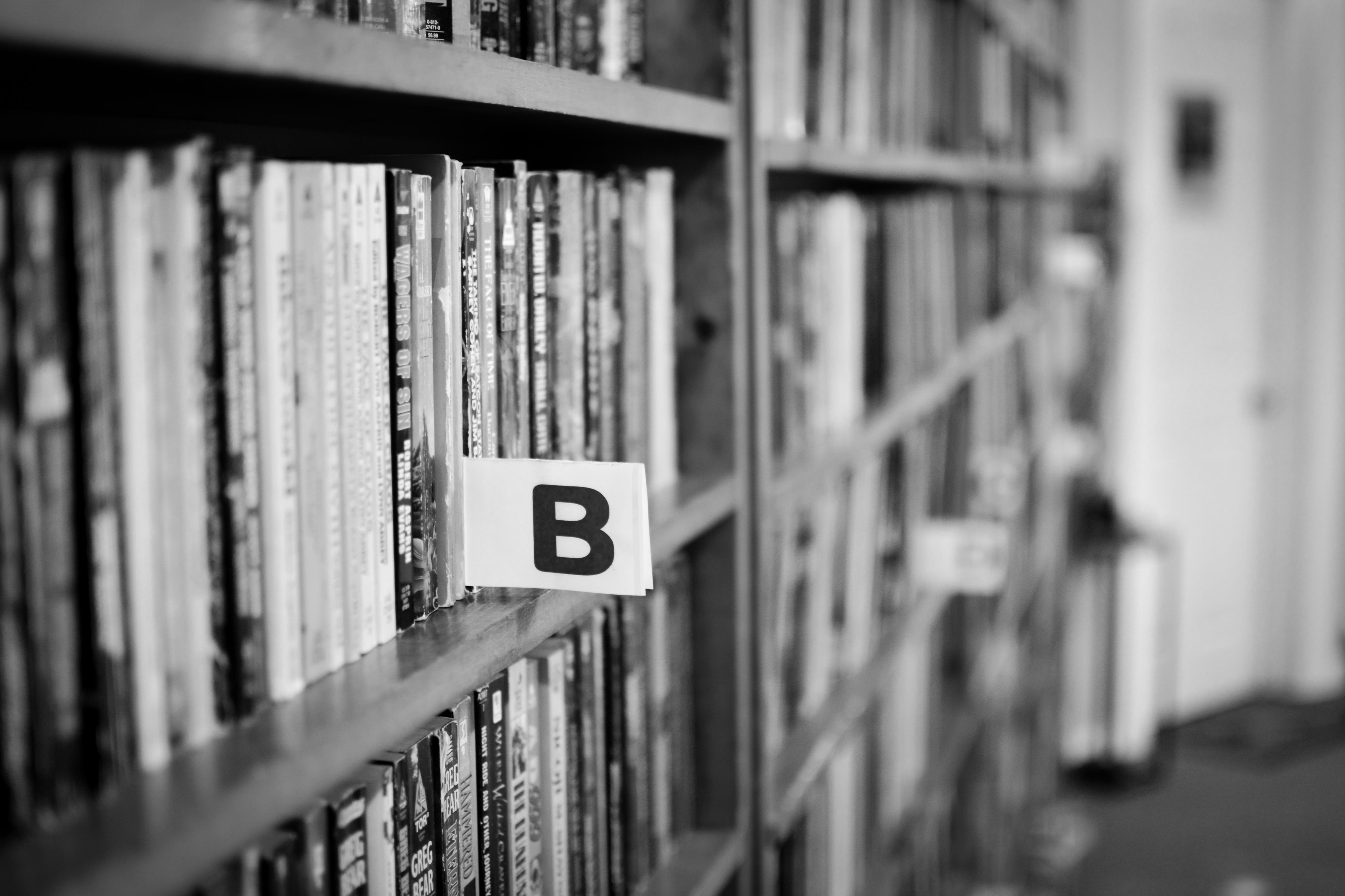 greyscale photo of b note in bookshelf