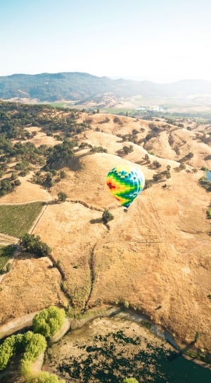 hot air balloon above ground near hills during daytime thumbnail