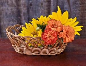 yellow and orange petaled flowers and brown woven oval basket thumbnail