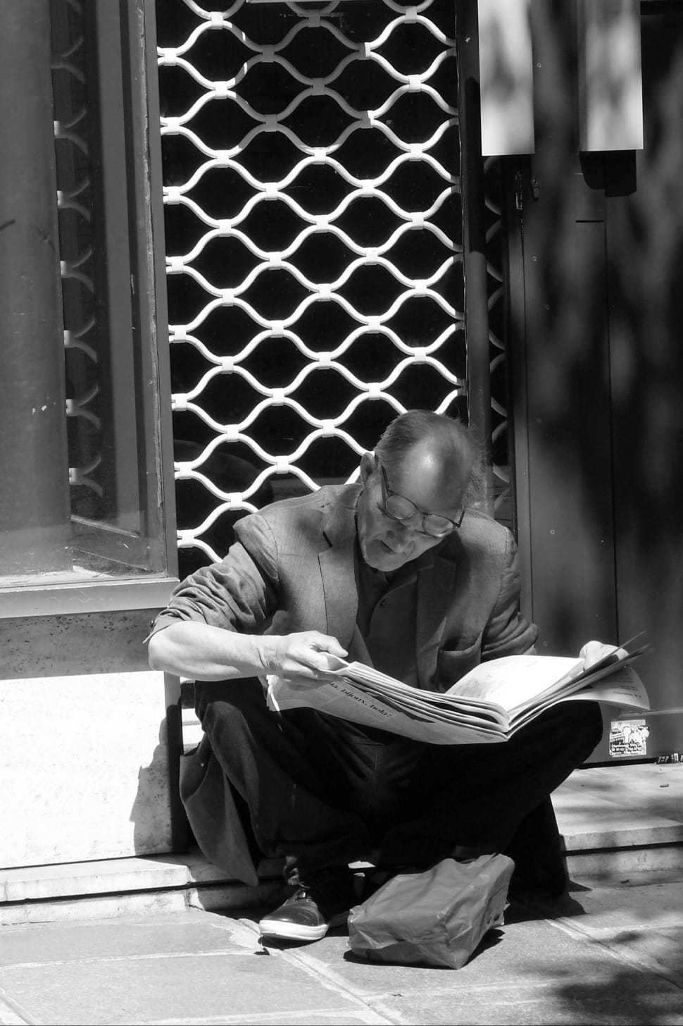 grayscale photo of man reading newspaper preview