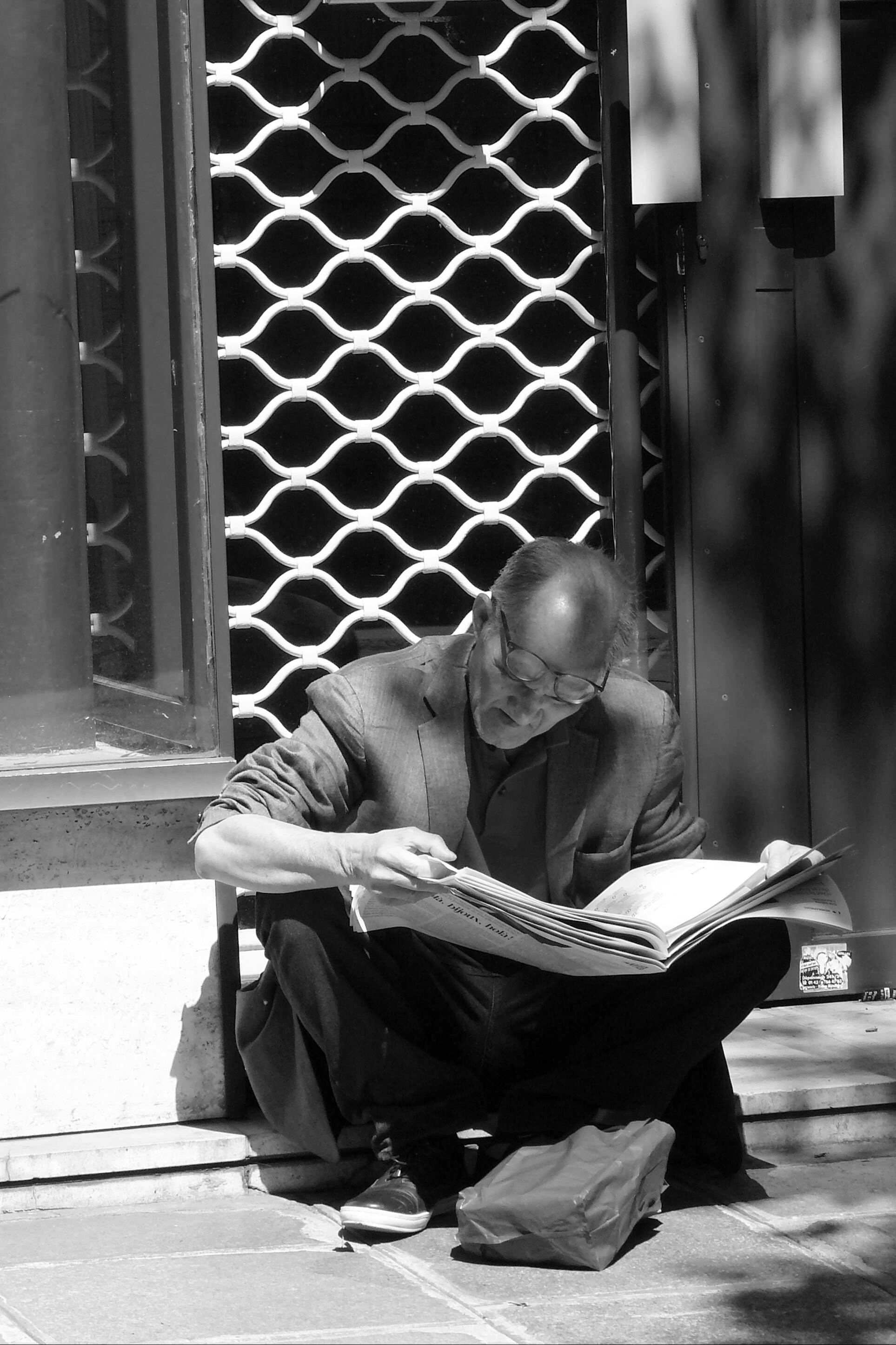 grayscale photo of man reading newspaper