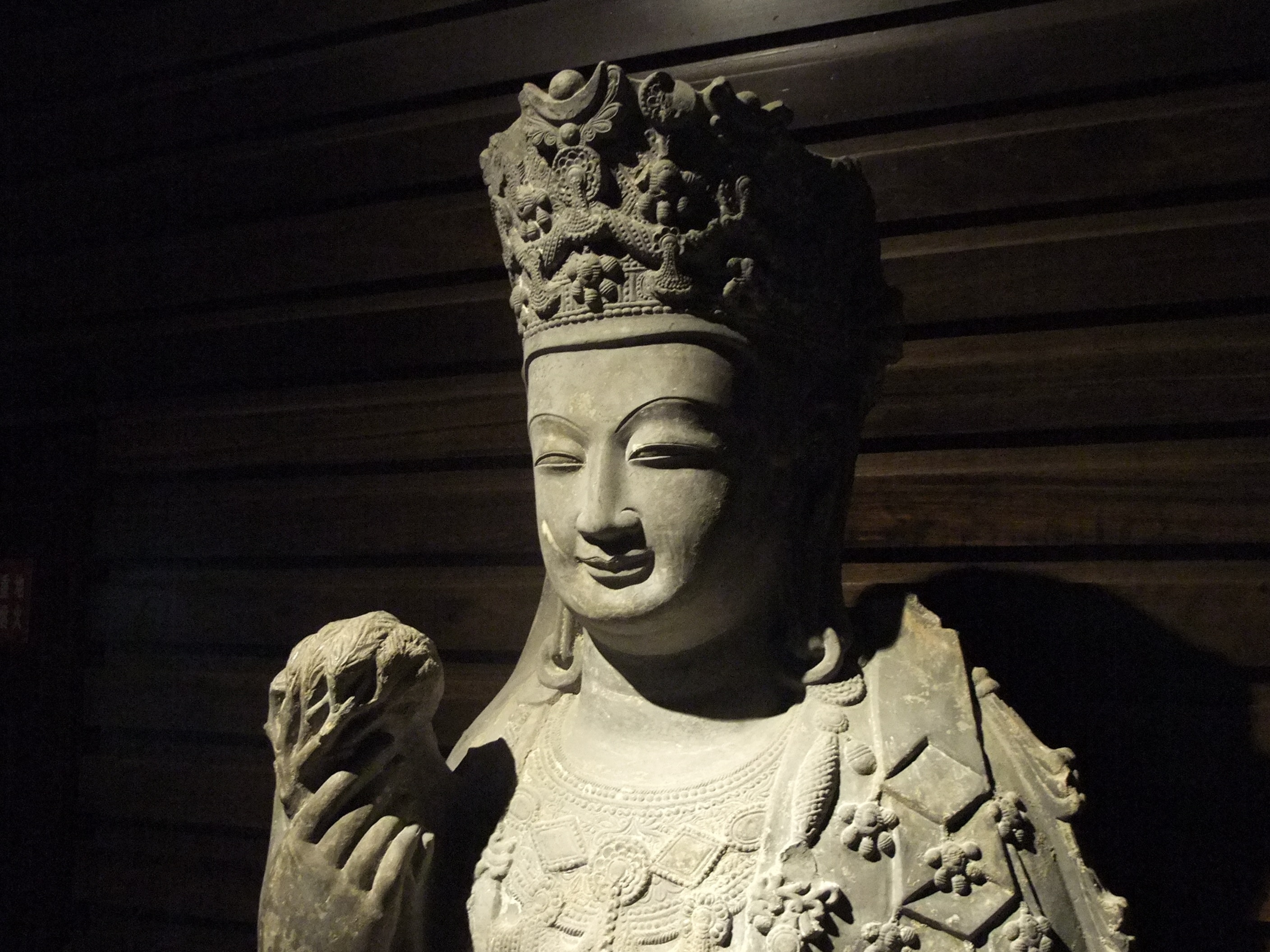 gray ceramic statue near brown wooden wall