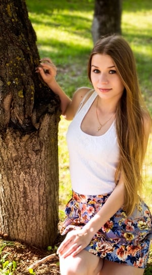 photo of woman in white tank top and blue floral skirt near tree and grasses thumbnail