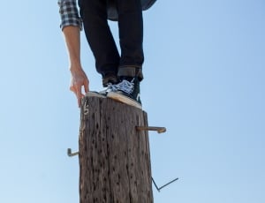 man wearing black jeans and black and white shirt standing on a tree trunk thumbnail