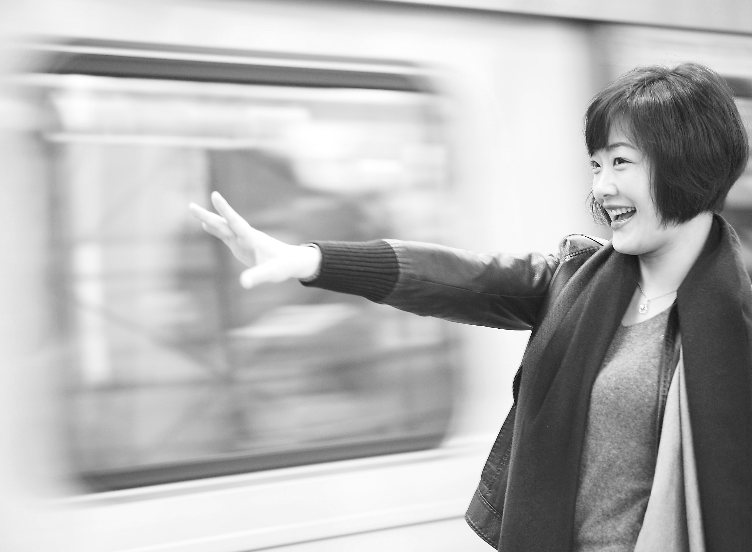 greyscale photo of time lapse woman wearing blazer besides train