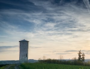grey concrete lighthouse near green grass field during daytime thumbnail