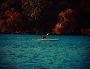 person doing kayak on sea near green and brown mountain during daytime thumbnail