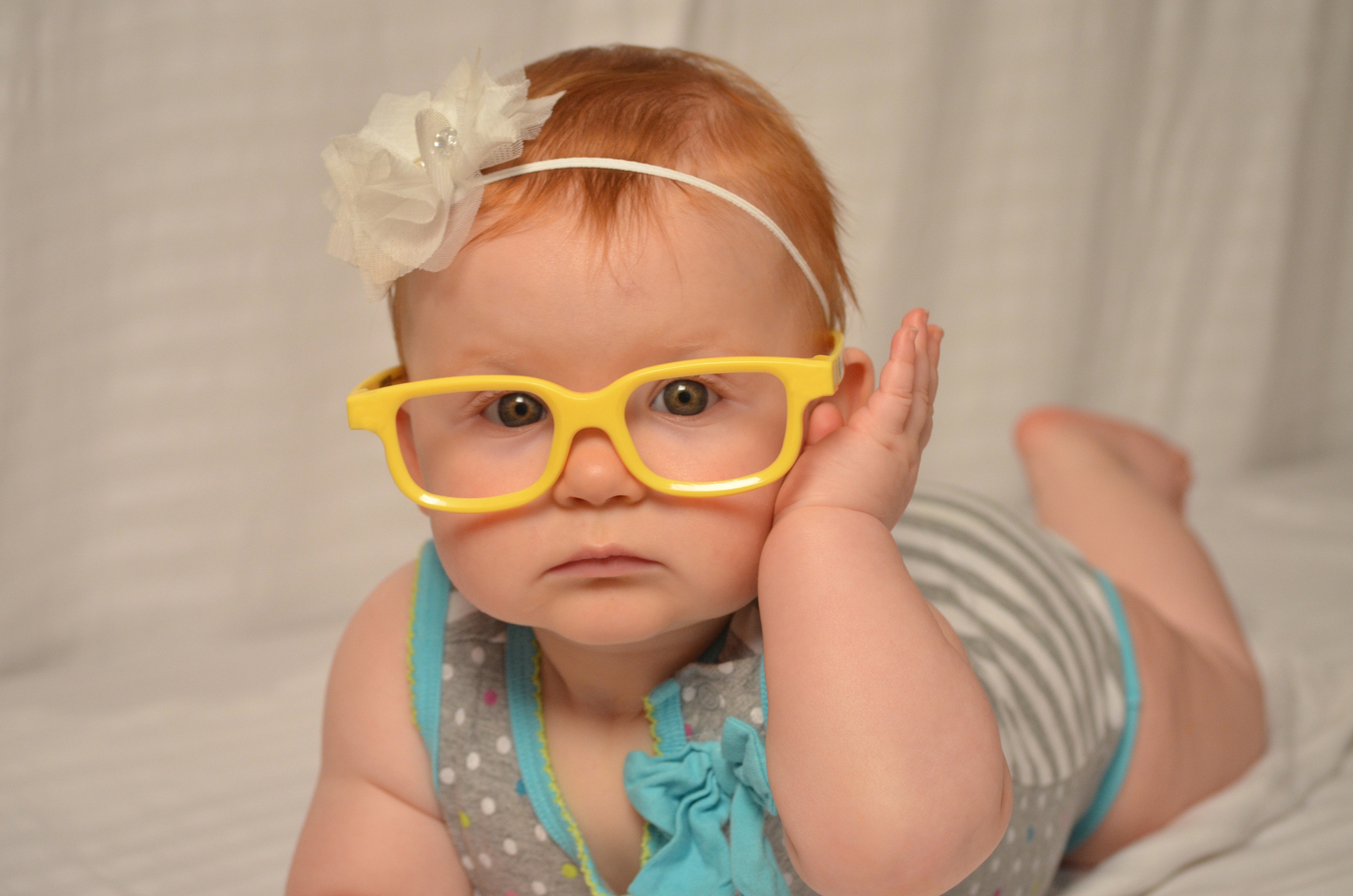 baby in yellow frame eye glass lying photo