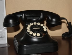 black rotary telephone on top of brown wooded surface thumbnail