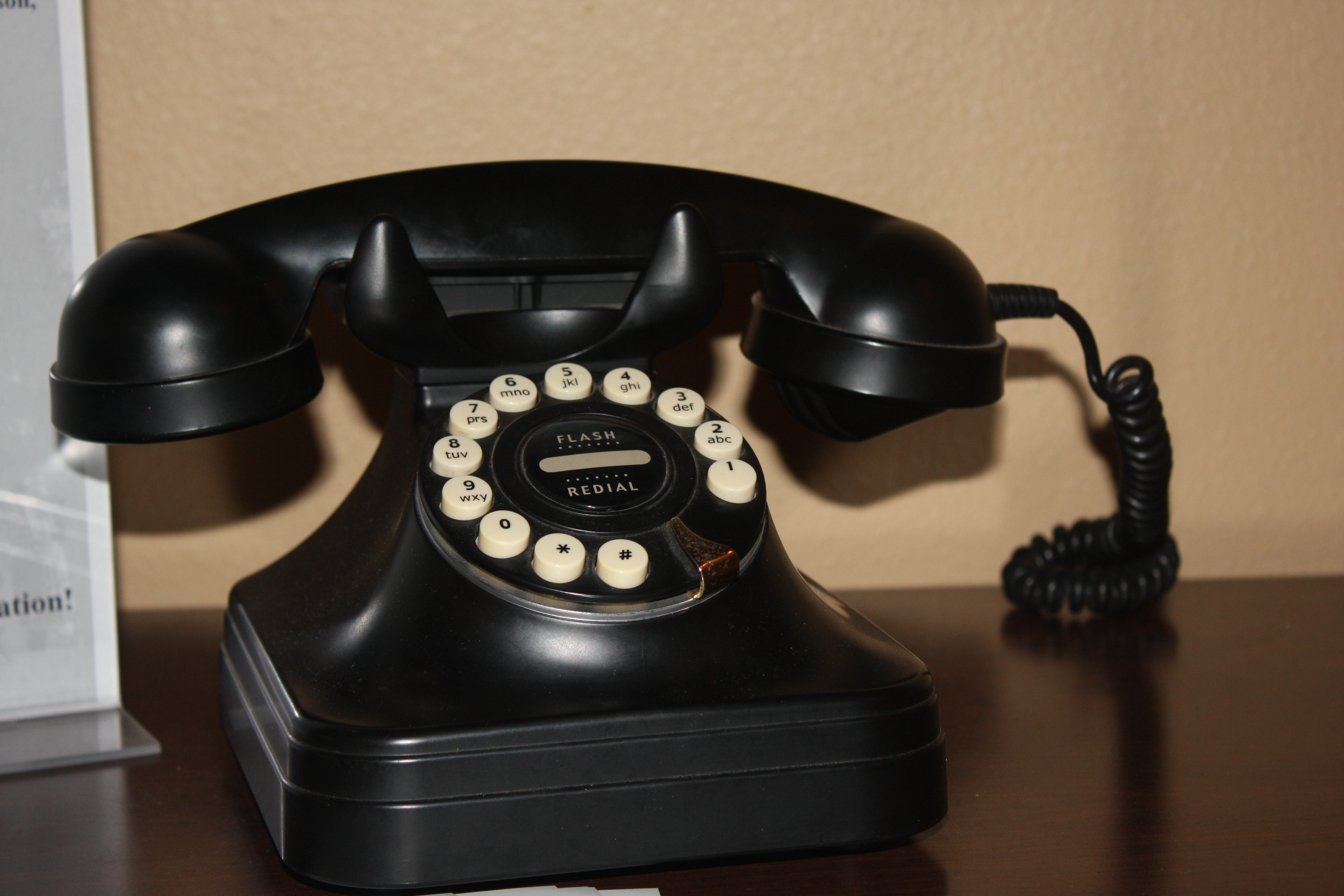 black rotary telephone on top of brown wooded surface