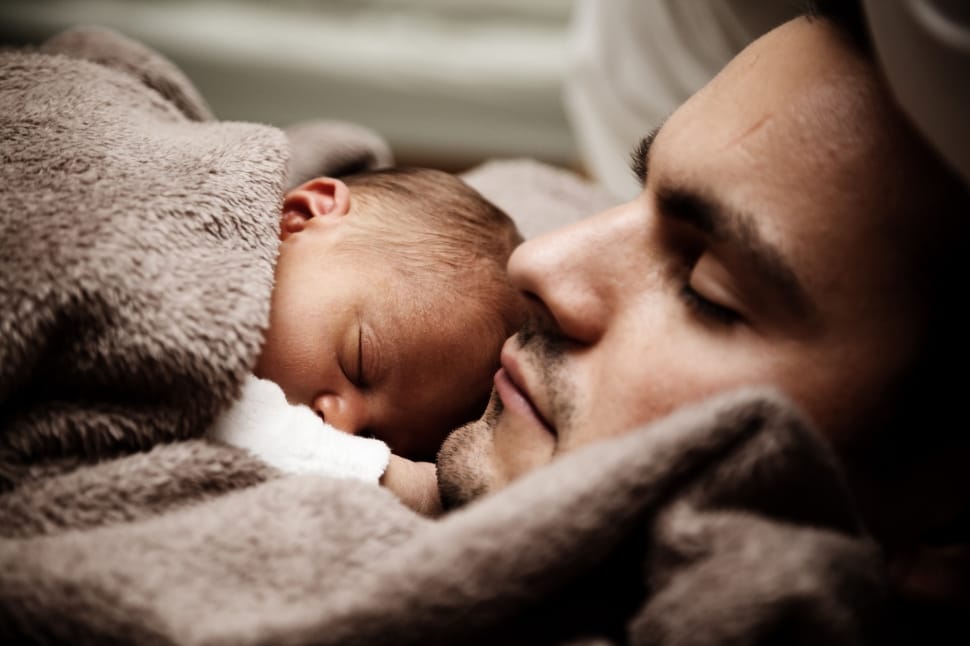 baby sleeping on man chest covered with gray fleece blanket preview