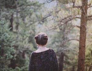 woman wearing black long sleeve dress near green leaves forest trees during day time thumbnail