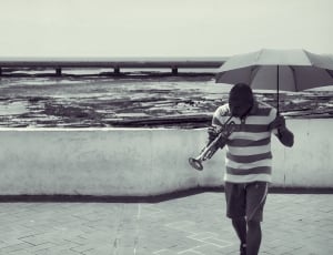 grayscale photo of a man holding a wind instrument thumbnail