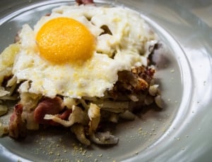 bacon with sunny side up egg topping on grey ceramic plate thumbnail