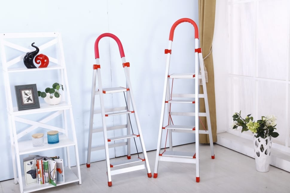two aluminum a-type ladders beside white wooden rack preview