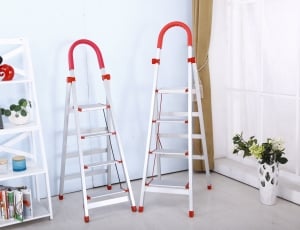 two aluminum a-type ladders beside white wooden rack thumbnail