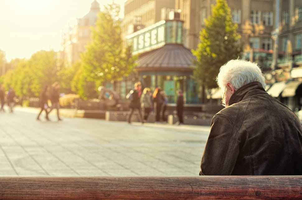 man in black leather jacket sitting on bench during daytime preview
