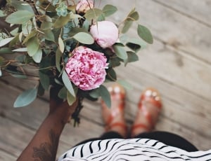 Person Holding Pink Flower Standing on Brown Wooden Floor thumbnail