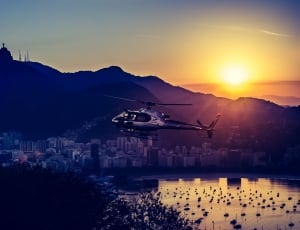 black and gray helicopter flying in mid-air during sunset thumbnail