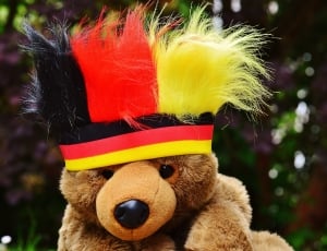 brown teddy bear wearing red and yellow headdress thumbnail