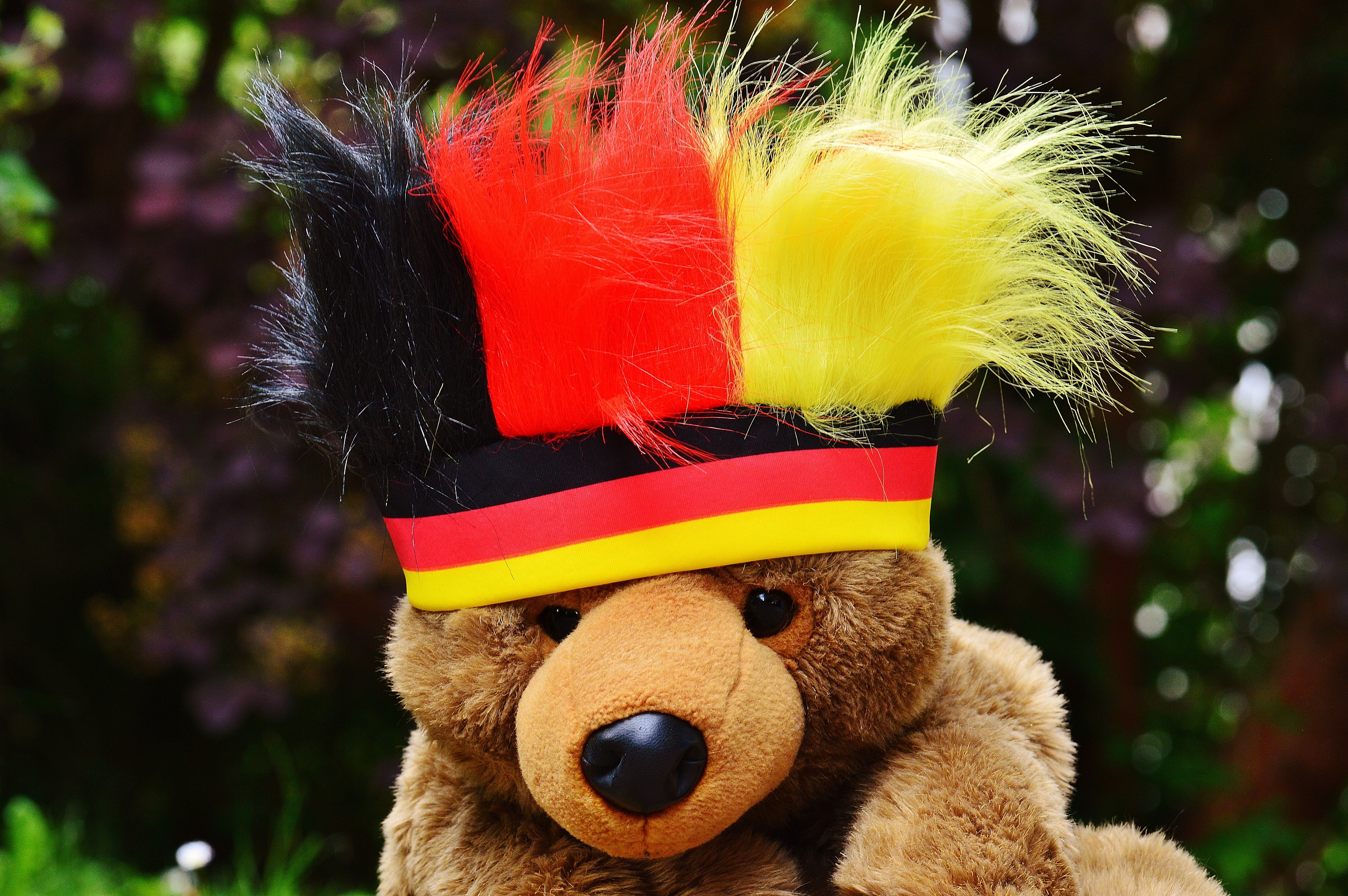 brown teddy bear wearing red and yellow headdress
