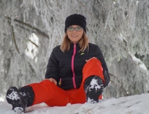 women's black bubble zip jacket sitting on snow during daytime thumbnail