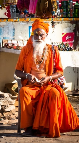 man in orange traditional dress sitting on armchair thumbnail