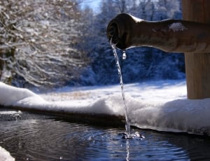 brown wooden faucet surrounded by snow during daytime thumbnail