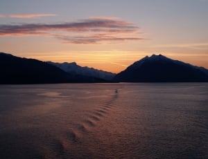 landscape photography of body of water with silhouette of mountain during golden hour thumbnail