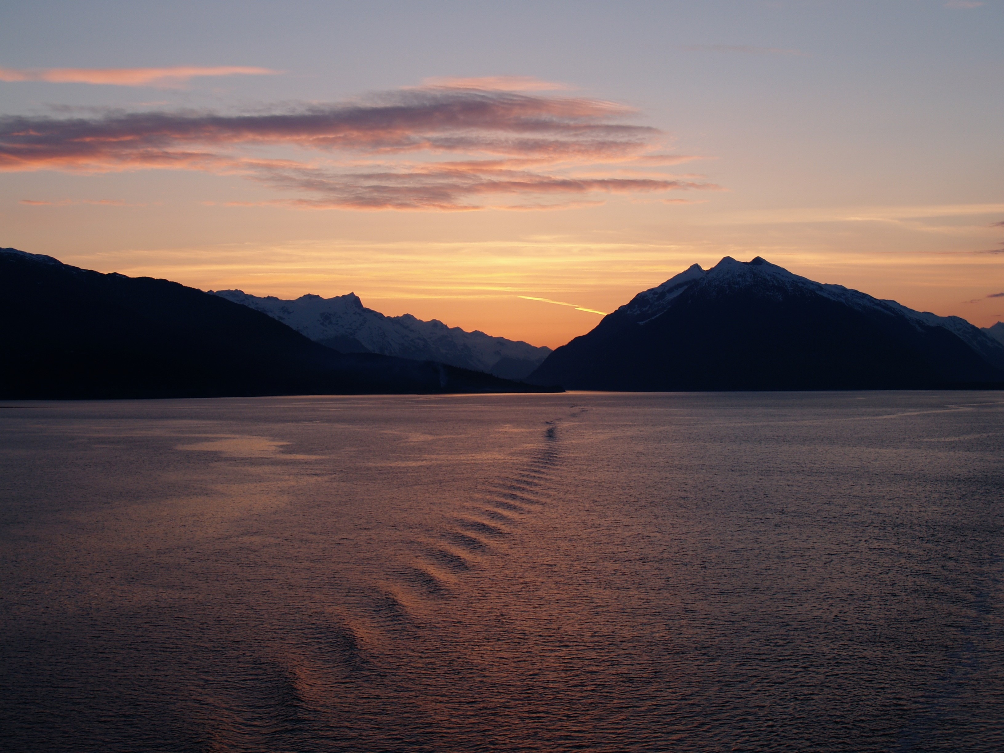 landscape photography of body of water with silhouette of mountain during golden hour