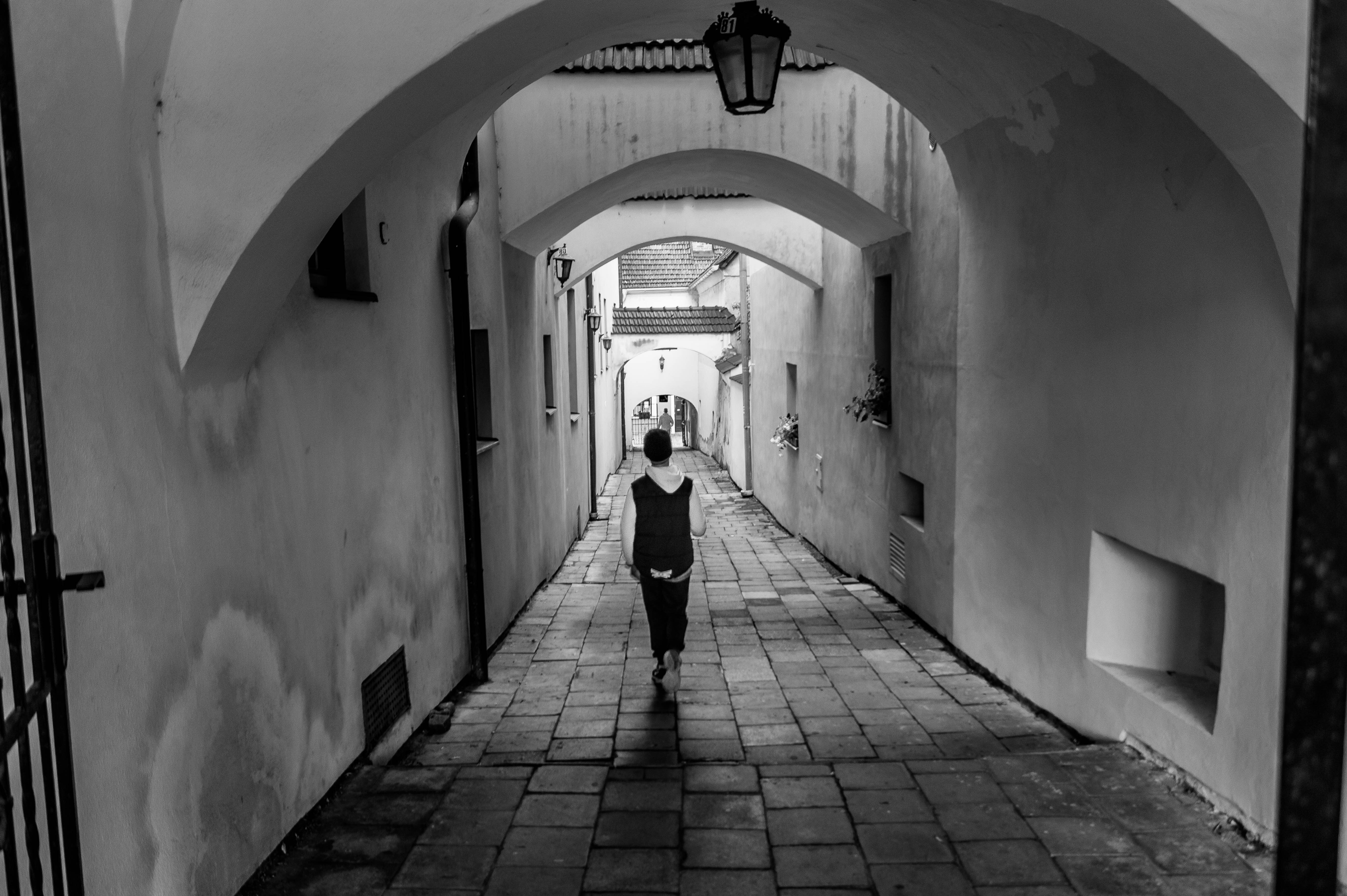 person walking the hallway grayscale photo
