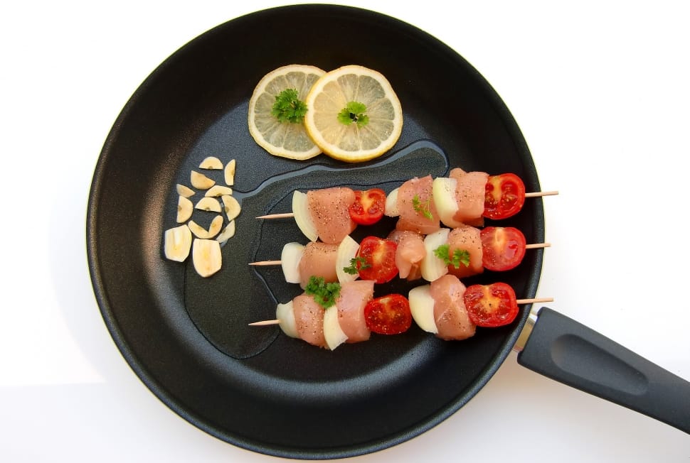 black cooking pot with meat and tomato skewers with lemon slices preview