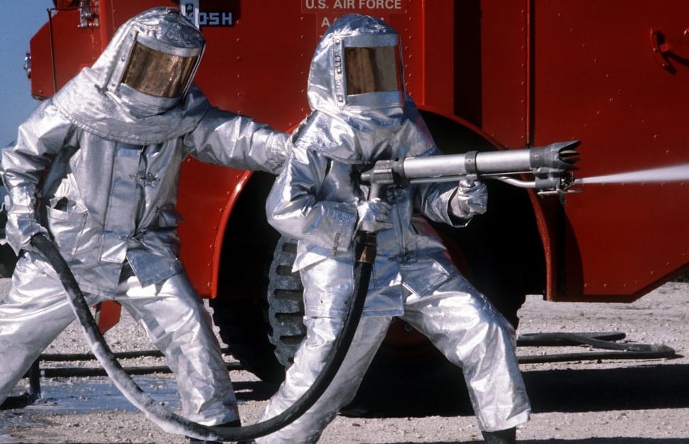 two person wearing silver suit holding spray gun near red truck preview