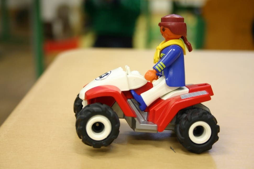 person riding atv mini figure on brown wooden table shallow focus photography preview