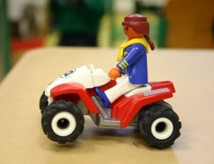 person riding atv mini figure on brown wooden table shallow focus photography thumbnail
