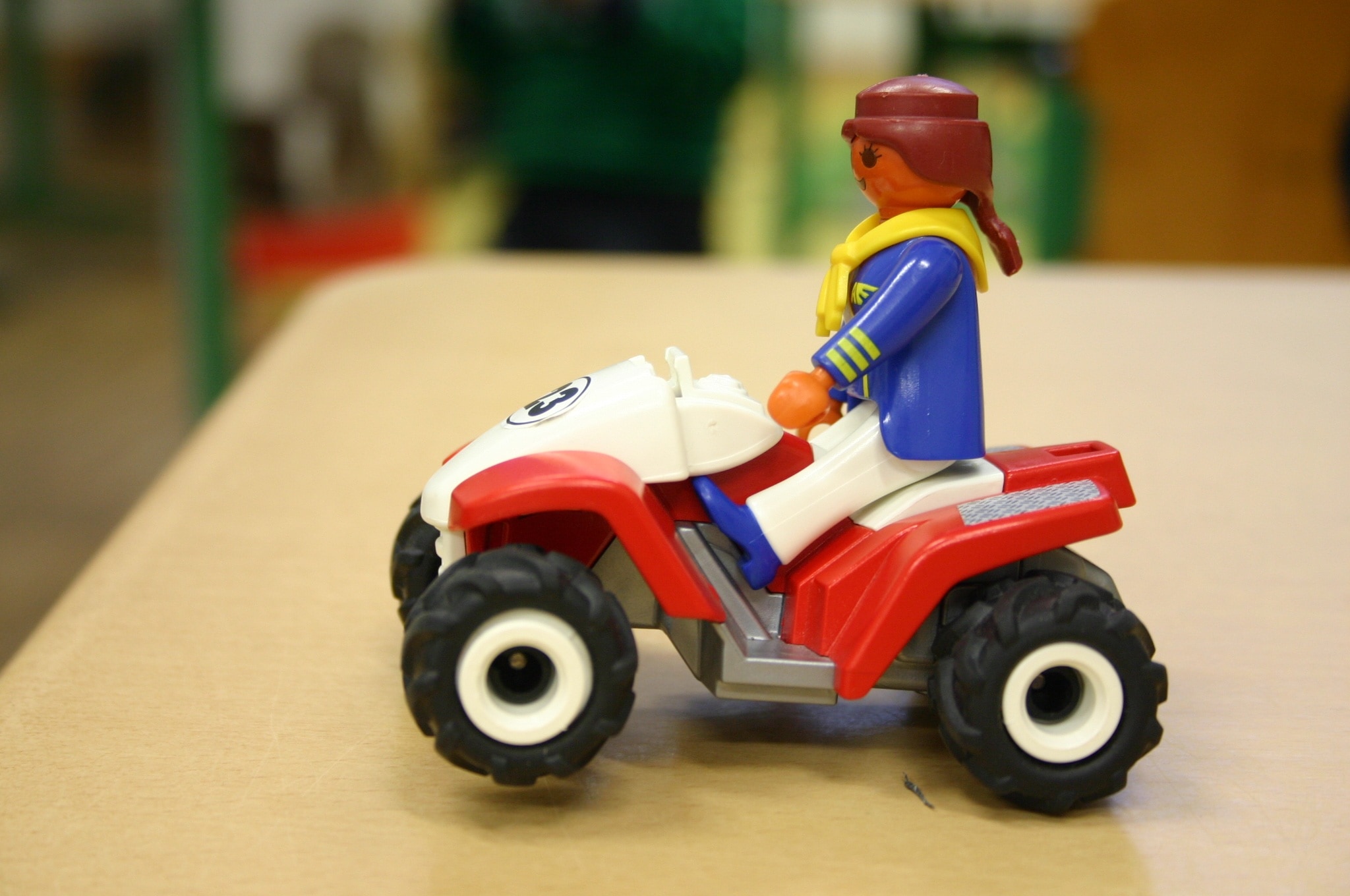 person riding atv mini figure on brown wooden table shallow focus photography
