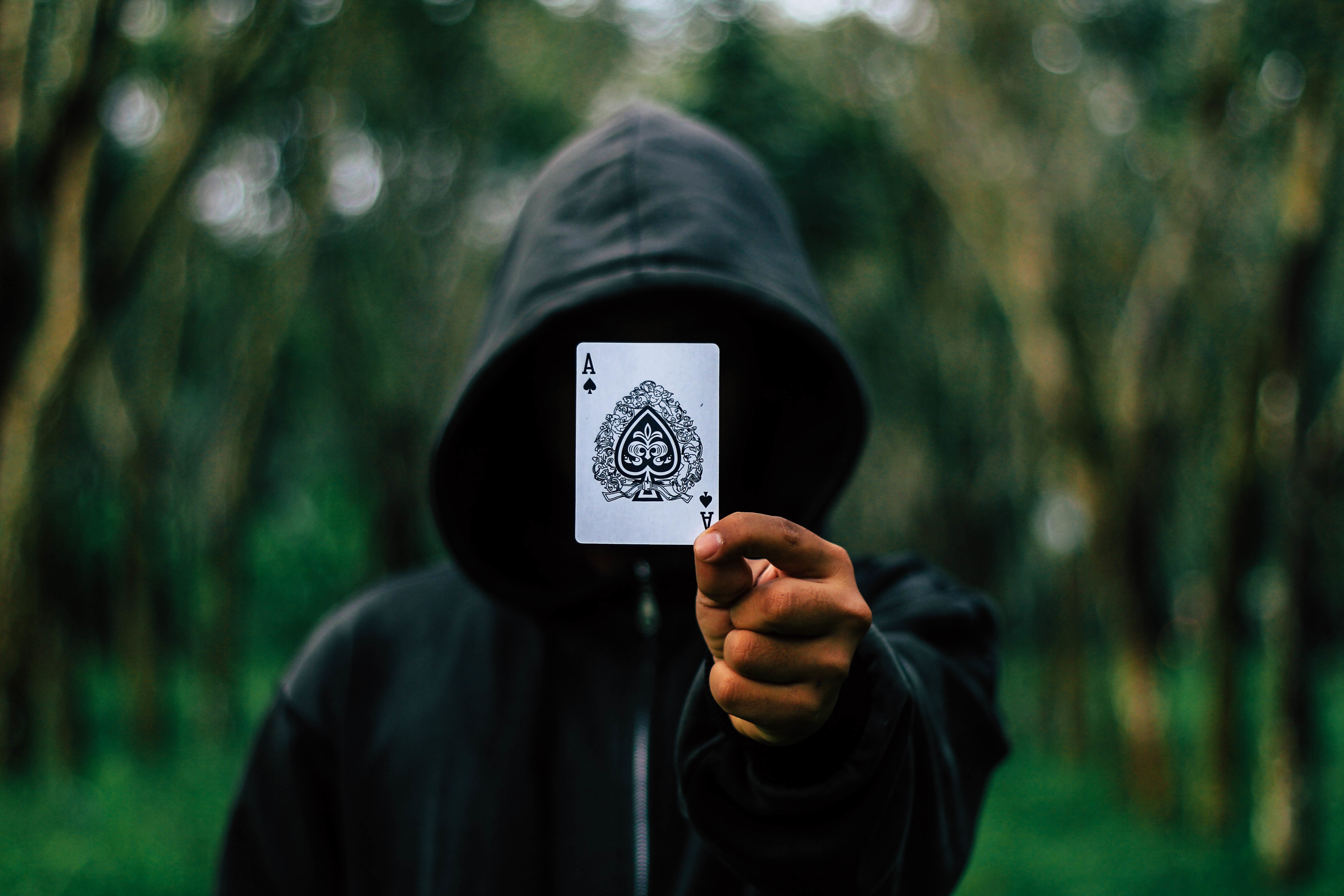 man holding ace of clubs card selective focus photography