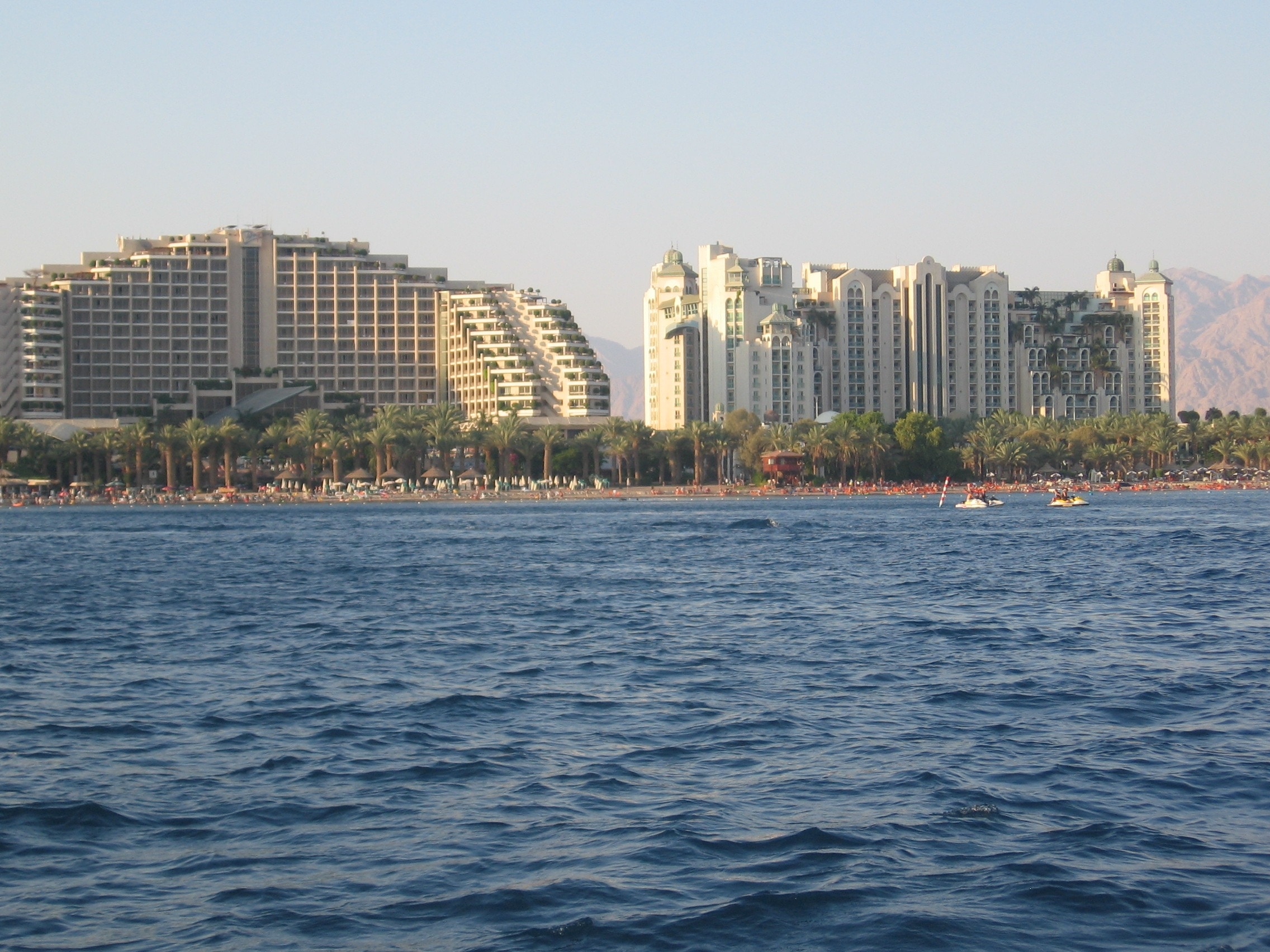 body of water near city with tall buildings under blue sky