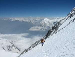 person wearing brown and black snowsuit in the middle of mountain covered with snow during daytime thumbnail